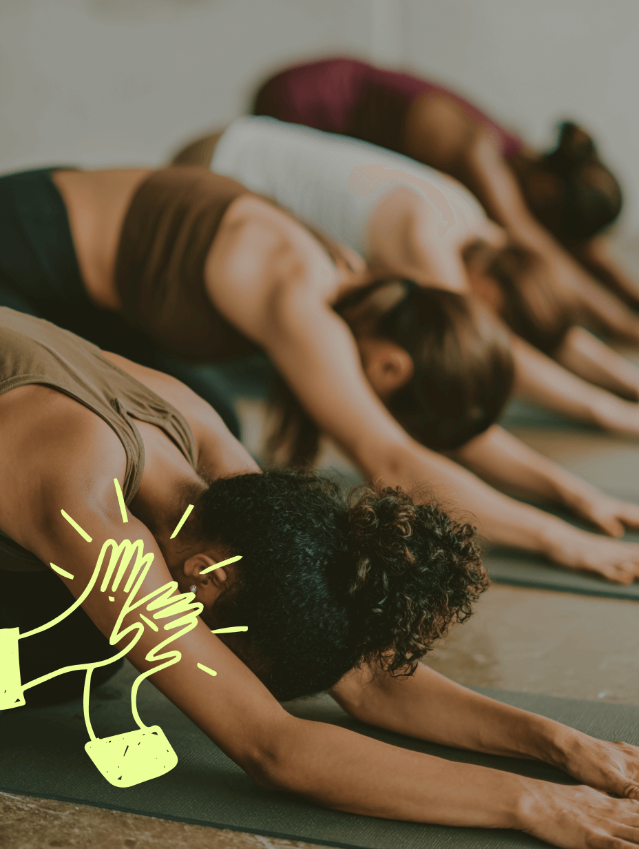 Group of people practicing yoga in a studio with a focus on one person's hands.